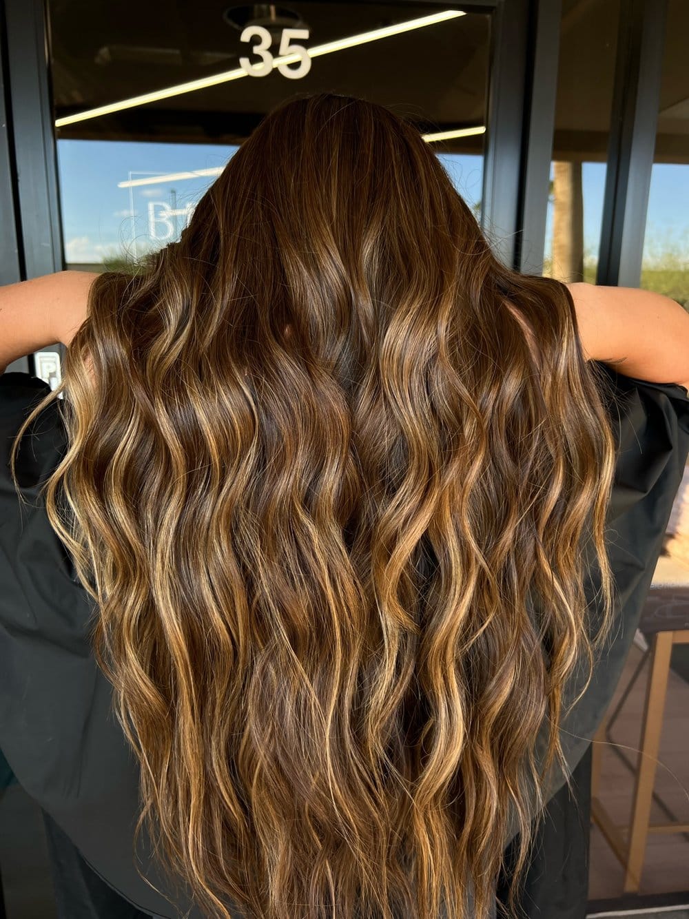 Long dimensional brunette balayage with caramel highlights and soft waves at Chandler AZ hair salon